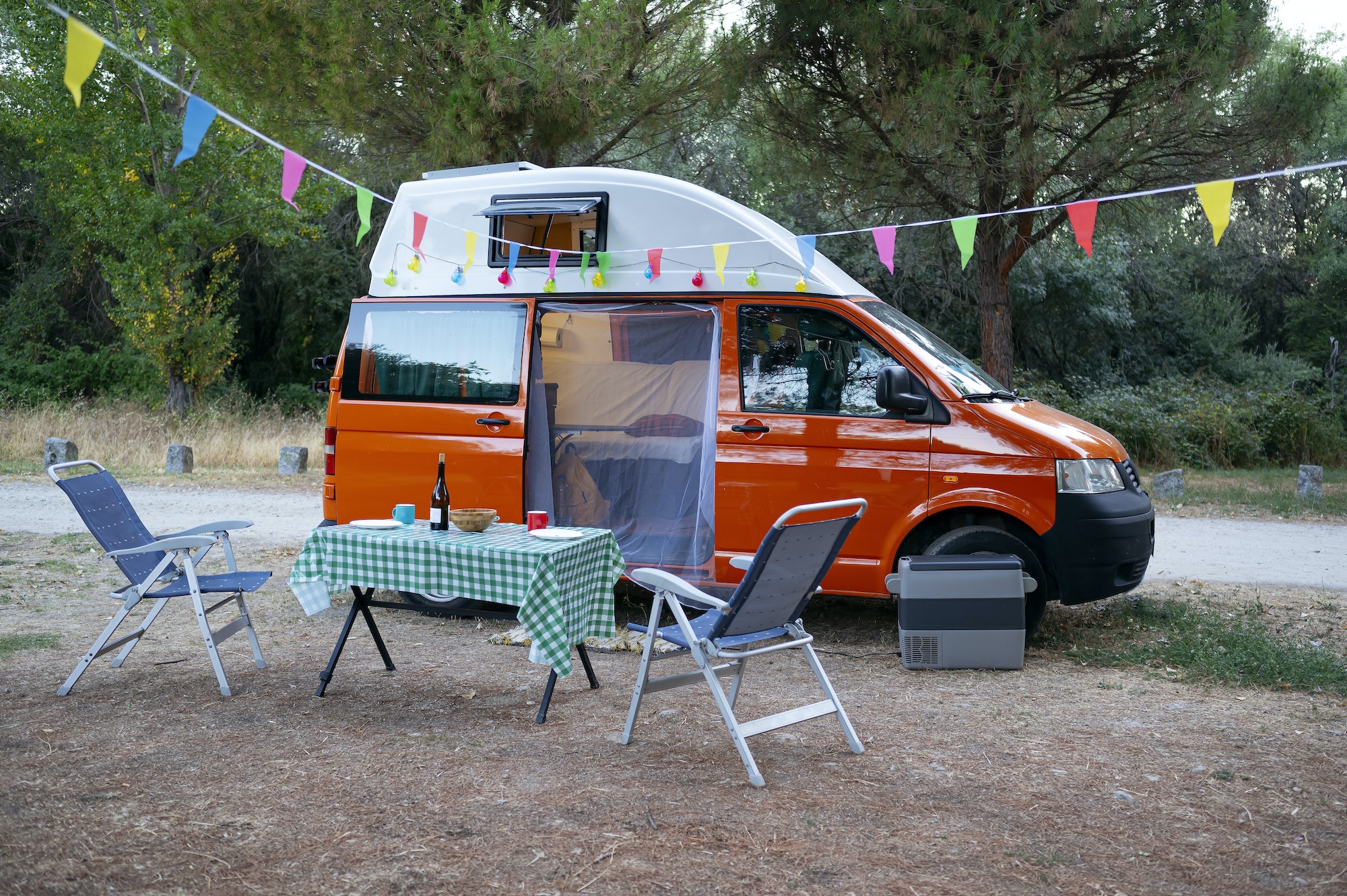 Camper van in the field with chairs and table for recreation. van life concept .